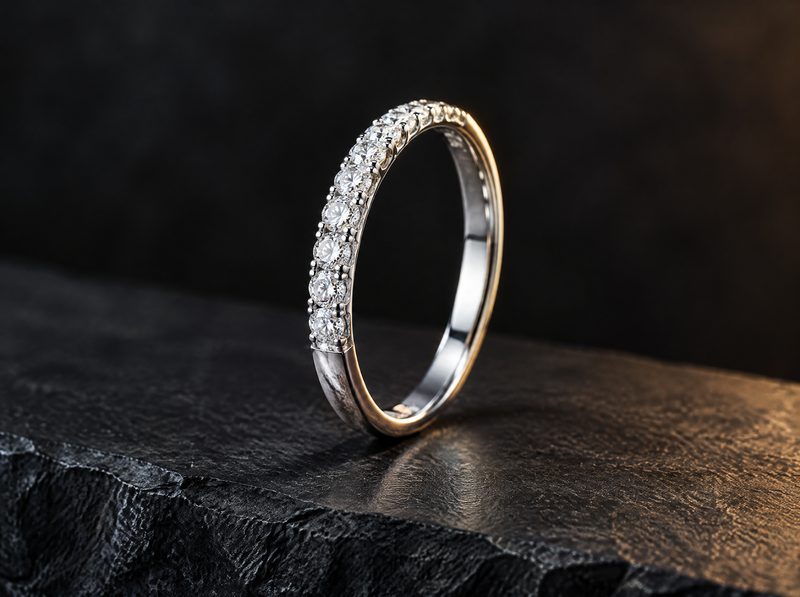 Halo: a women's white gold band with a row of small pave-set stones, standing on dark slate.
